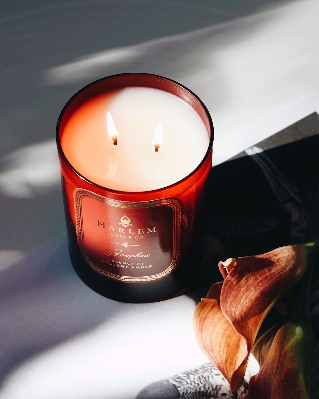 This is a lifestyle image of our Josephine candle illuminated next to flowers