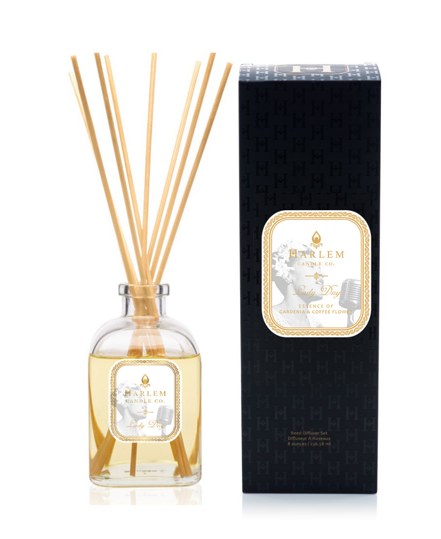Lady Day reed diffuser bottle with natural reeds next to its black textured packaging box on a white background.