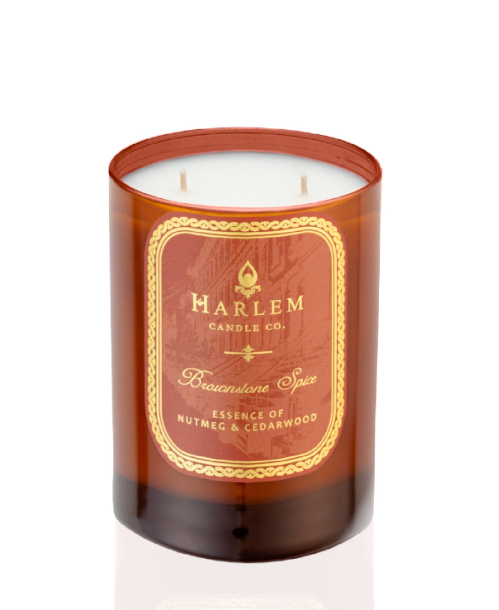 This is an image of the Brownstone Spice Candle in an amber colored glass on a white background.