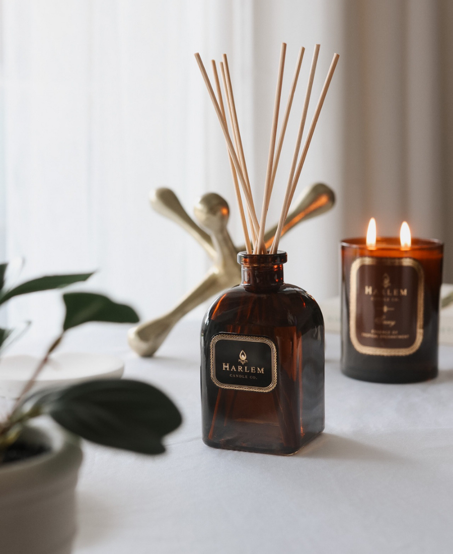 Savoy Reed Diffuser on a white table with greenery, a gold paperweight and the Savoy Candle.