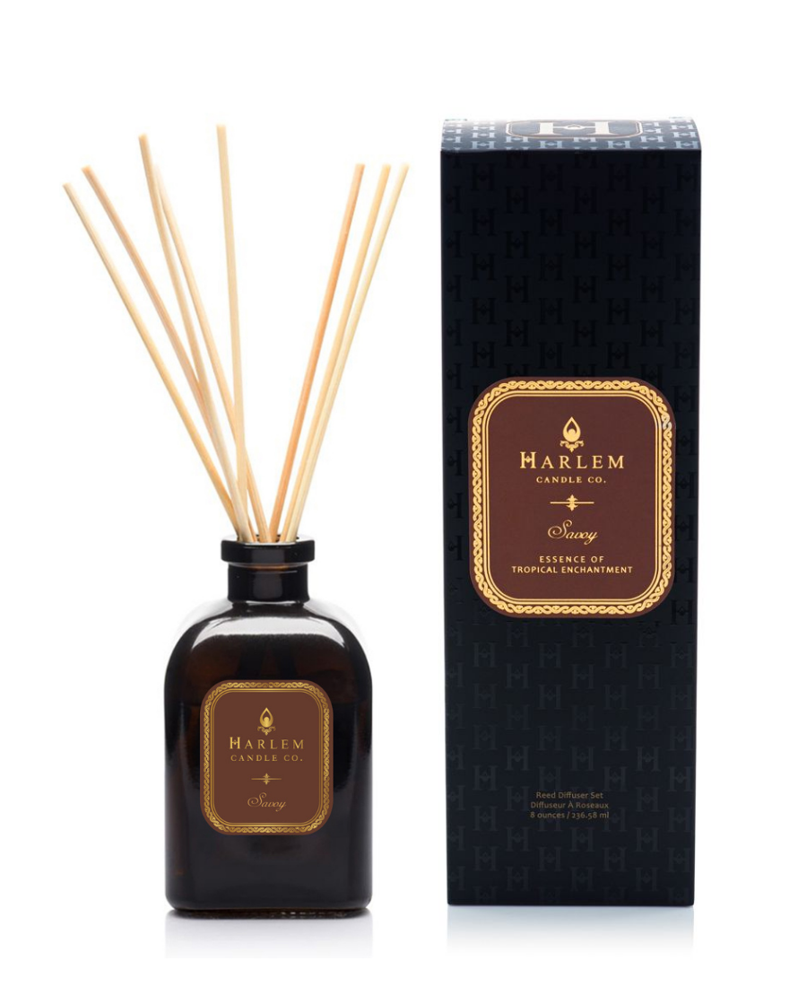 Savoy reed diffuser bottle with natural reeds next to its black textured packaging box on a white background.