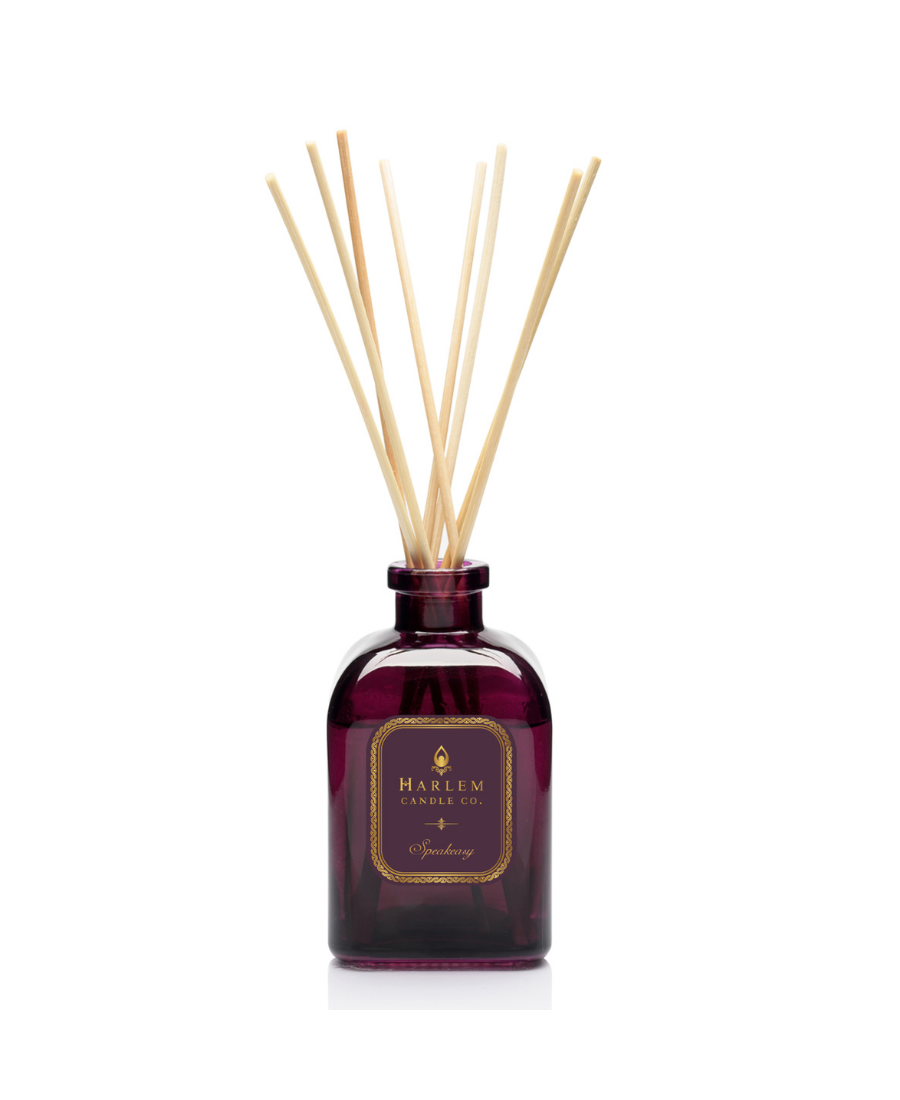 Speakeasy reed diffuser bottle filled with multiple natural wood reed sticks rising above the top, set against a plain white background.