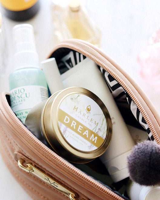 A lifestyle Image of our gorgeous Dream Candle beautifully displayed inside a pink makeup case on a white floral table.